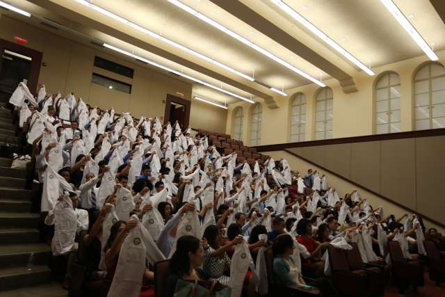 A lecture hall of new medical students holding white coats
