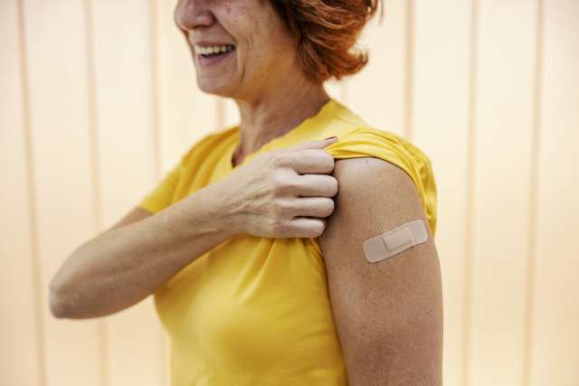 A woman shows the band-aid on her right arm, following her flu shot