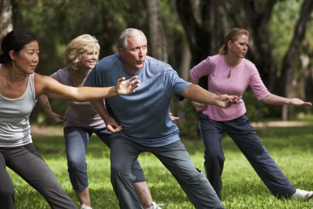 A group of adults practicing Tai Chi in a park.