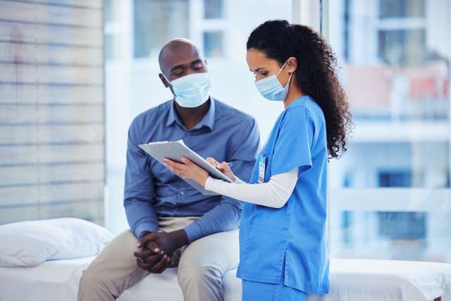 Doctor consultation, mask and patient results of a nurse with a black man in a hospital. Clinic, covid conversation and nursing communication with medical data and healthcare discussion for advice.