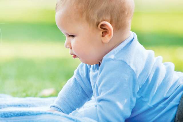 Baby lying on blanket outdoors