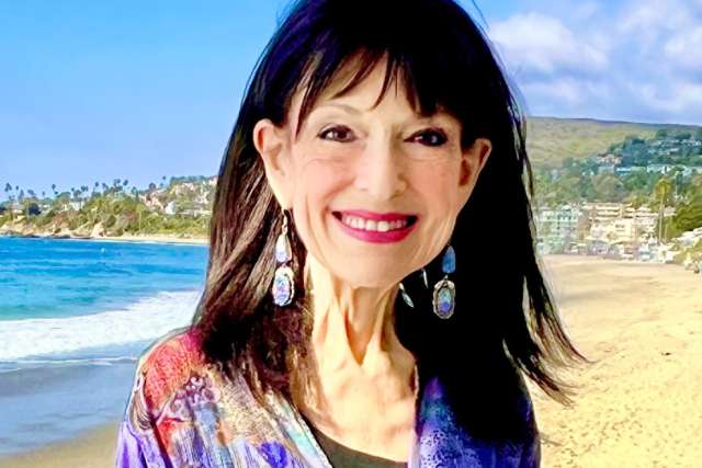 Debra Gold stands with the coastline in the background.