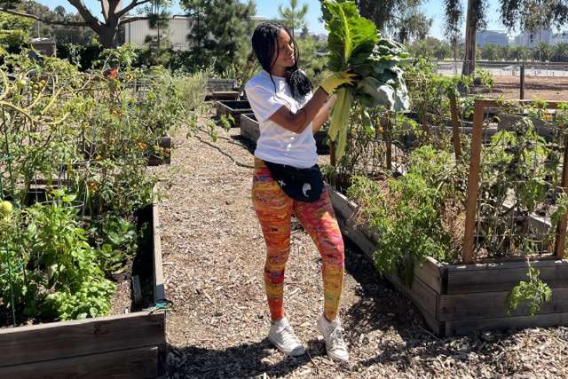 U.S. Air Force Veteran Cyntrea Cotton holds up produce at the Veteran's Garden where she volunteers.