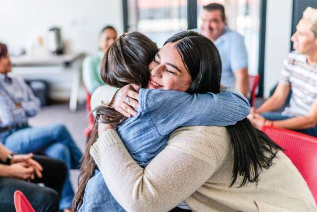 Two women hugging at a support group meeting