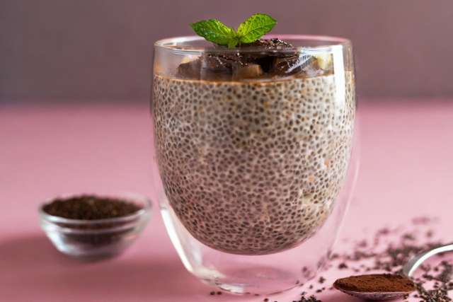 A glass of Chocolate-Peanut Butter Chia Pudding on pink background
