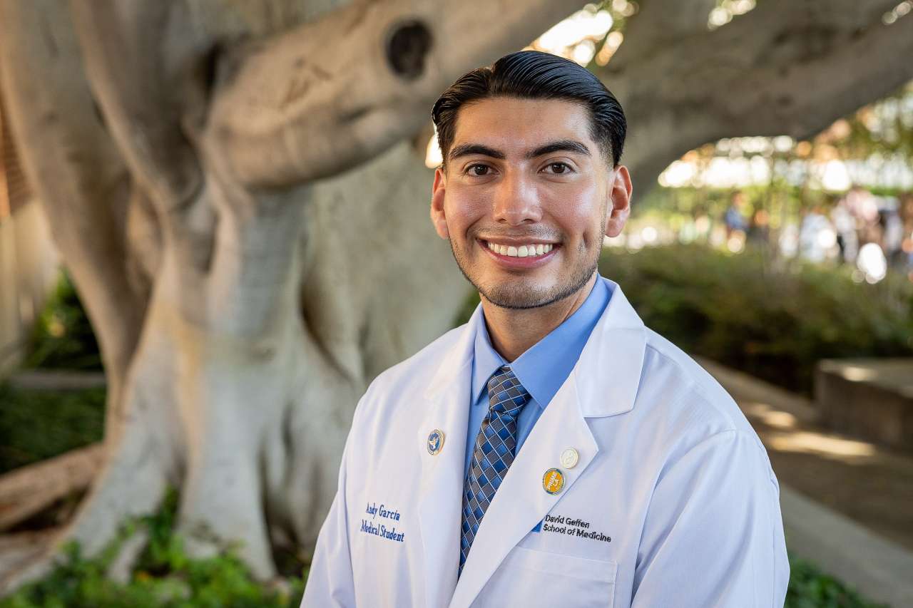 Medical student Andy Garcia poses for a photo in his white coat.