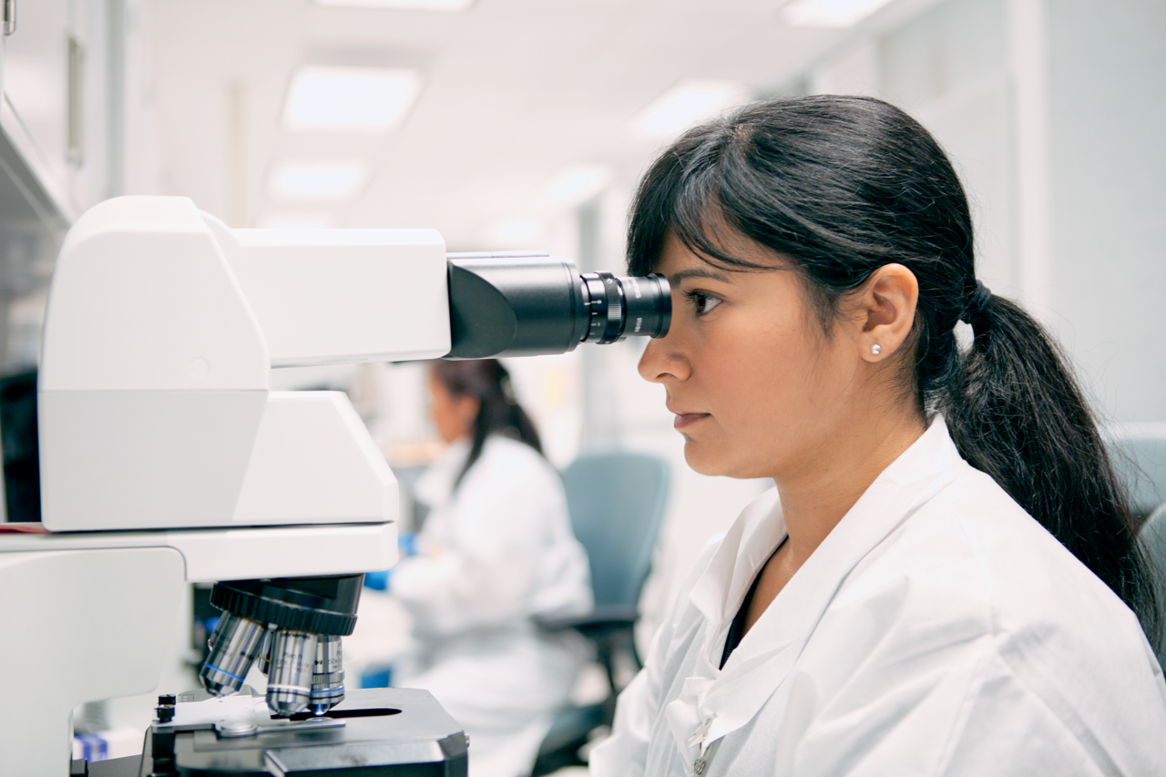 technician looking through microscope