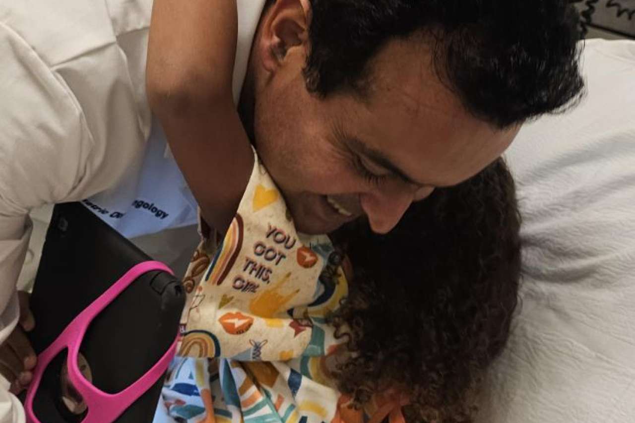 Dr. Sohit Kanotra hugs Keona Mock in a hospital bed