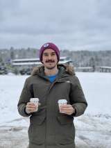 Joshua Hubert, DO, MS skiing in Vermont with two cups of coffee