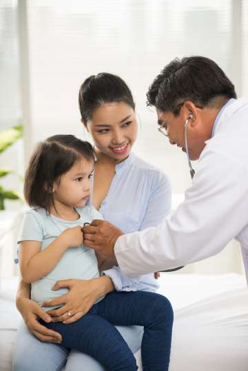 Doctor assessing child patient while mother holds her