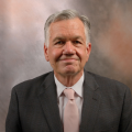 headshot of doctor greg Brent in grey suit