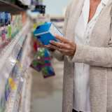 A woman looks at the label of an over-the-counter medicine in a pharmacy.
