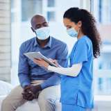 Doctor consultation, mask and patient results of a nurse with a black man in a hospital. Clinic, covid conversation and nursing communication with medical data and healthcare discussion for advice.