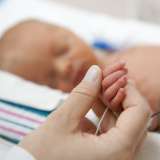 Baby in the NICU holding on to mom's hand.